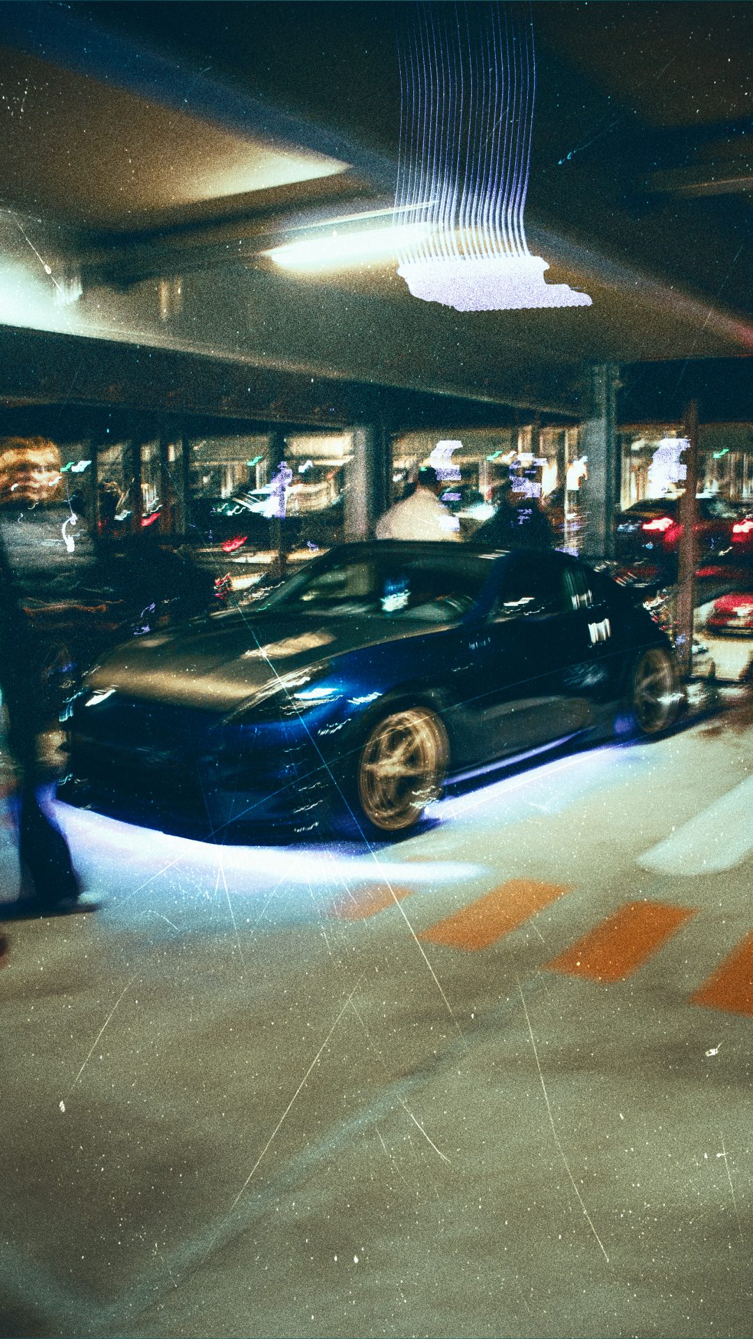Dunkles Fahrzeug mit Bewegung und Lichtspuren in einer urbanen Nachtlocation.